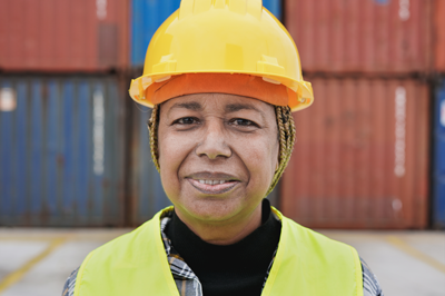 Smiling woman wearing a hard hat in a shipping yard